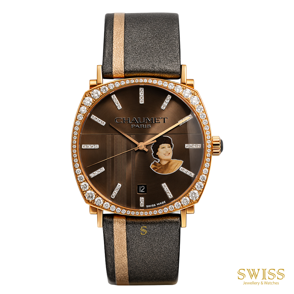 A luxury wristwatch by Chaumet Paris, featuring a gold-tone case encrusted with clear crystals, a brown dial with a portrait of Queen Elizabeth II, and a dark brown leather strap with gold stripes.